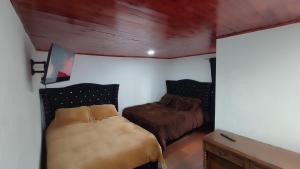 a bedroom with two beds in a room with wood ceilings at Cabañas Casa Campo Guatavita in Guatavita