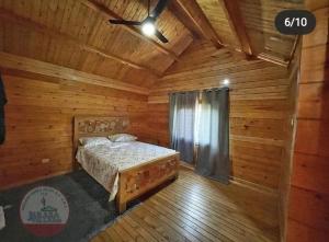 a bedroom with a bed in a wooden cabin at Villa encantadora pino alto J4 in Jarabacoa