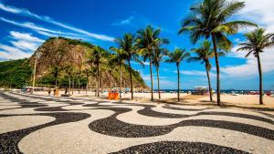 uma vista para uma praia com palmeiras e uma formação rochosa em Conforto de copa na quadra da praia no Rio de Janeiro