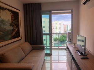 a living room with a couch and a large window at Apt tip flat midas riocentro jeunesse arena in Rio de Janeiro