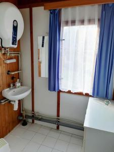 a bathroom with a sink and a window with blue curtains at Chata Kubíček na Šumavě in Prachatice