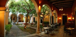 a courtyard with tables and chairs and trees in a building at Hotel Boutique La Mision De Fray Diego in Mérida