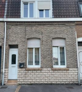 - un bâtiment en briques avec deux fenêtres et une porte blanche dans l'établissement #GREENHOME#, à Dunkerque
