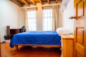 a bedroom with a blue bed and two windows at Hermosa, Enorme y Céntrica Casa Toluca y Metepec in Toluca