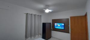 a room with a ceiling fan and a tv on the wall at Casa de Hóspedes em Parque Pinheiros - Sem Garagem in Taboão da Serra