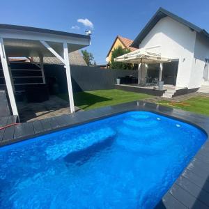 a blue swimming pool in front of a house at Nemes Apartmanház Tóalmás in Tóalmás