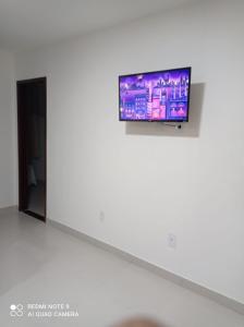 a flat screen tv hanging on a wall at Residencial Jardim Imbassai 4 apt mobiliado com piscina in Mata de Sao Joao
