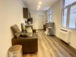 sala de estar con sofá marrón y cocina en Appartement 003, en Angleur