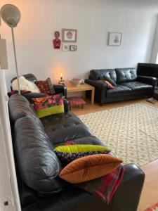 a living room with a black leather couch with pillows at Charming 3 Bedroom Apartment in the Heart of Vibrant Old Town in Edinburgh