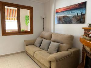 ein braunes Sofa im Wohnzimmer mit Fenster in der Unterkunft Acogedor apartamento a escasos metros de la playa in Santa Pola