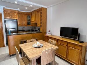 eine Küche mit einem Holztisch und einem TV auf der Theke in der Unterkunft Acogedor apartamento a escasos metros de la playa in Santa Pola