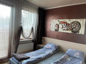 ein Schlafzimmer mit einem Bett und einem Motorrad-Gemälde an der Wand in der Unterkunft Top of the Mountain Гранд Манастира частни Апартаменти in Pamporowo