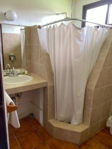 a bathroom with a shower with a sink and a shower curtain at HOTEL UTZTZABA in Monterrico
