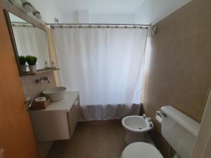 a bathroom with a white toilet and a sink at Duplex Laguna in Puerto Madryn