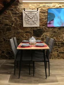 einen Tisch mit Stühlen und eine Uhr an der Wand in der Unterkunft A Caseta in A Coruña