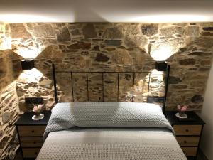 a bedroom with a stone wall with a bed and two lamps at A Caseta in A Coruña