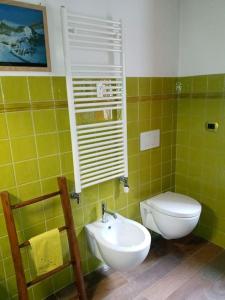 a green tiled bathroom with a toilet and a sink at Appartamento raccolto con terrazzo e parcheggio in Antey-Saint-André