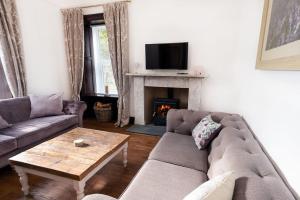 a living room with a couch and a fireplace at Cosy 200 Year Old Listed Cottage Near to St Andrews in Markinch