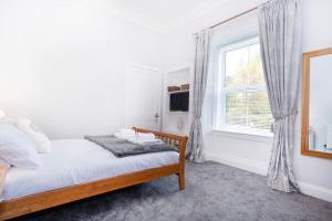 a white bedroom with a bed and a window at Cosy 200 Year Old Listed Cottage Near to St Andrews in Markinch