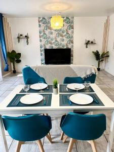 une salle à manger avec une table blanche et des chaises bleues dans l'établissement Le cosy en cœur de ville, à Prades