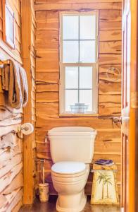 baño con aseo y ventana en The Cedar House at Creekside Camp & Cabins, en Marble Falls
