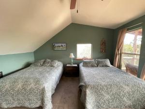 2 camas en un dormitorio con paredes verdes en The Cedar House at Creekside Camp & Cabins, en Marble Falls