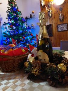 a bottle of wine on a table next to a christmas tree at Family House in Buşteni