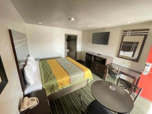 um pequeno quarto de hotel com uma cama e uma secretária em REGENCY INN - CHANNELVIEW em Channelview