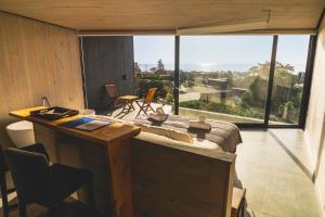 a room with a large window and a desk with a view at Pichilemu Domos in Pichilemu