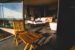 a wooden chair sitting on a balcony with a bed at Pichilemu Domos in Pichilemu