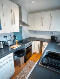 a kitchen with white cabinets and black counter tops at Comfortable equipped House in Nuneaton sleeps5 with FREE parking in Nuneaton