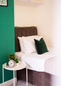Una cama con almohadas verdes y blancas y una mesa. en Comfortable equipped House in Nuneaton sleeps5 with FREE parking, en Nuneaton