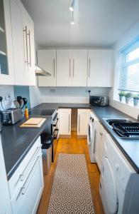 a kitchen with white cabinets and a black counter top at Comfortable equipped House in Nuneaton sleeps5 with FREE parking in Nuneaton