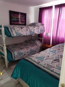 two beds in a room with purple curtains at MANUIA in Coquimbo +30 photos