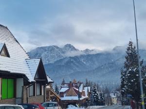 una città con edifici innevati e montagne sullo sfondo di Karpielówka 77 pokoje gościnne a Kościelisko