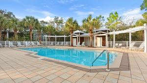 Una piscina con una casa y palmeras. en Grateful By the Sea, en Santa Rosa Beach