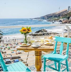 a table with chairs and a view of the beach at Hotel Cocó Cochoa in Viña del Mar