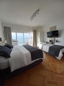 two beds in a bedroom with a view of the ocean at Hotel Cocó Cochoa in Viña del Mar