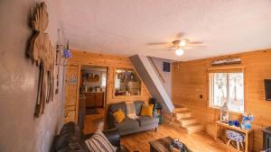 Charming Blue Farmhouse Cabin في Duck Creek Village: غرفة معيشة مع أريكة ومروحة سقف