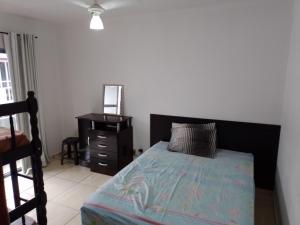 a bedroom with a bed with a black headboard and a dresser at Casa Matinhos in Matinhos