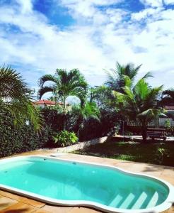 a swimming pool in a yard with palm trees at casa amar guaibim in Guaibim