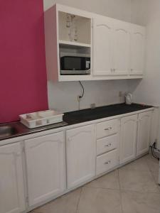 a kitchen with white cabinets and a microwave at Pondbottom Apartment Hotel in Saint James