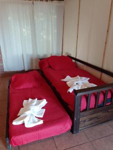1 dormitorio con 2 camas con sábanas rojas y toallas blancas en Cabaña San José en San Rafael