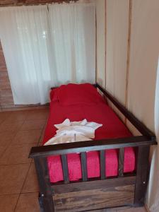 Cama pequeña en habitación con manta roja en Cabaña San José en San Rafael