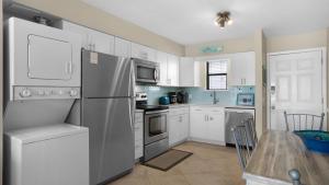 Beachside Condo 11 في شاطئ سانتا روزا: مطبخ مع أجهزة بيضاء وطاولة طعام