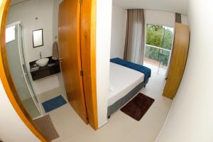 Habitación pequeña con cama y espejo. en Apartamentos Sinhá, en Penha