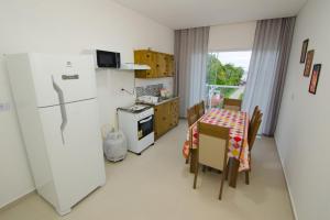 uma cozinha com um frigorífico branco e uma mesa com cadeiras em Apartamentos Sinhá em Penha