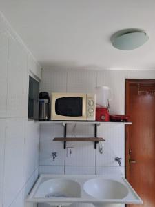 a small kitchen with two sinks and a microwave at Bangalô/Dúplex Jacumã Conde in Jacumã