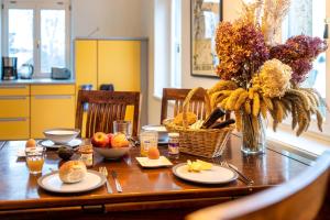 una mesa de madera con comida y un jarrón de flores en NUUMIS luxury 115 m2 Apartment, Dresdner Heide mit Garten, en Dresden