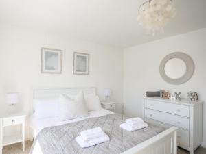a white bedroom with a bed and a mirror at Bryn Llifon in Pentraeth